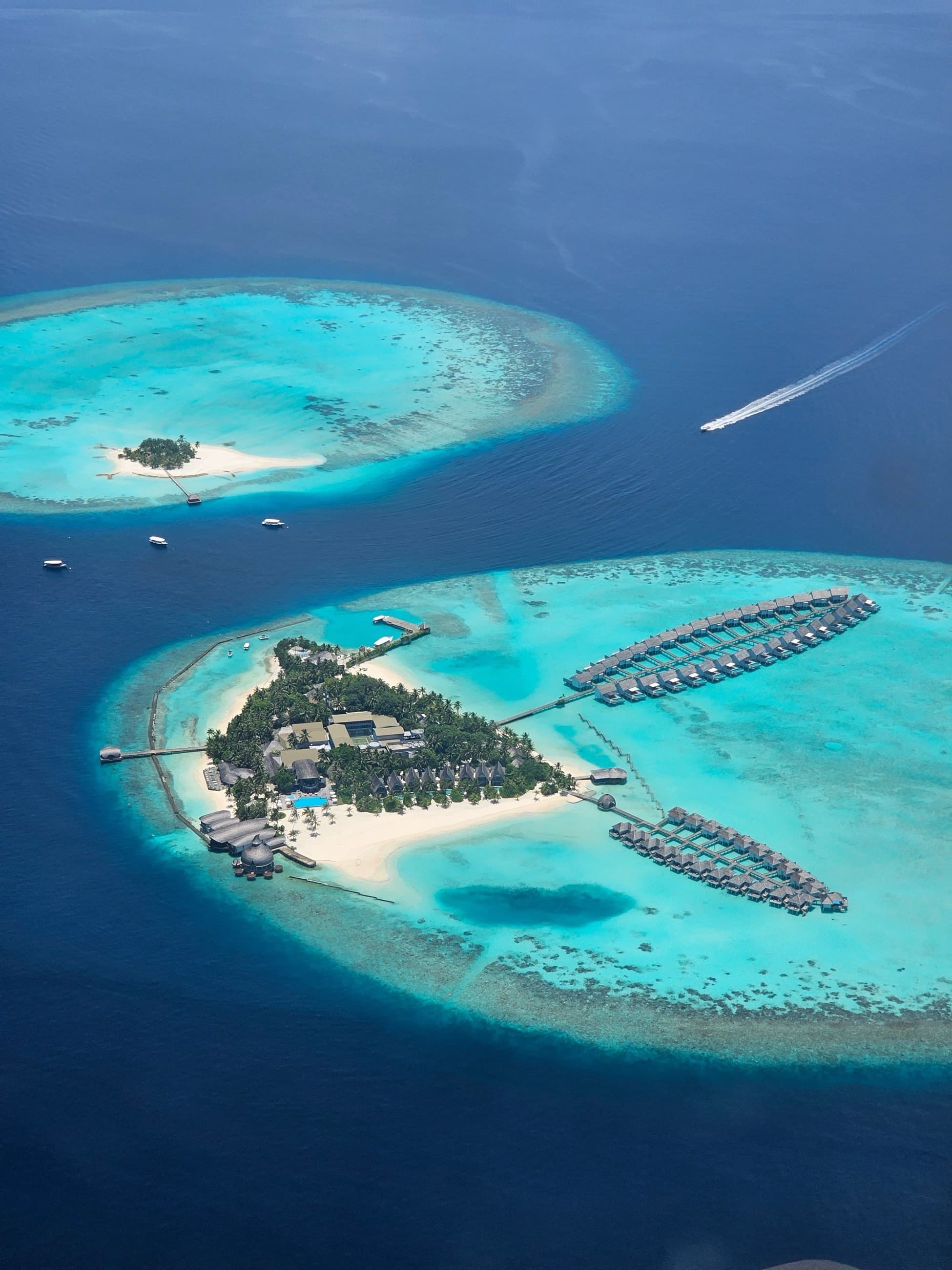 Aerial view of an island resort's overwater bungalows within a coral atoll
