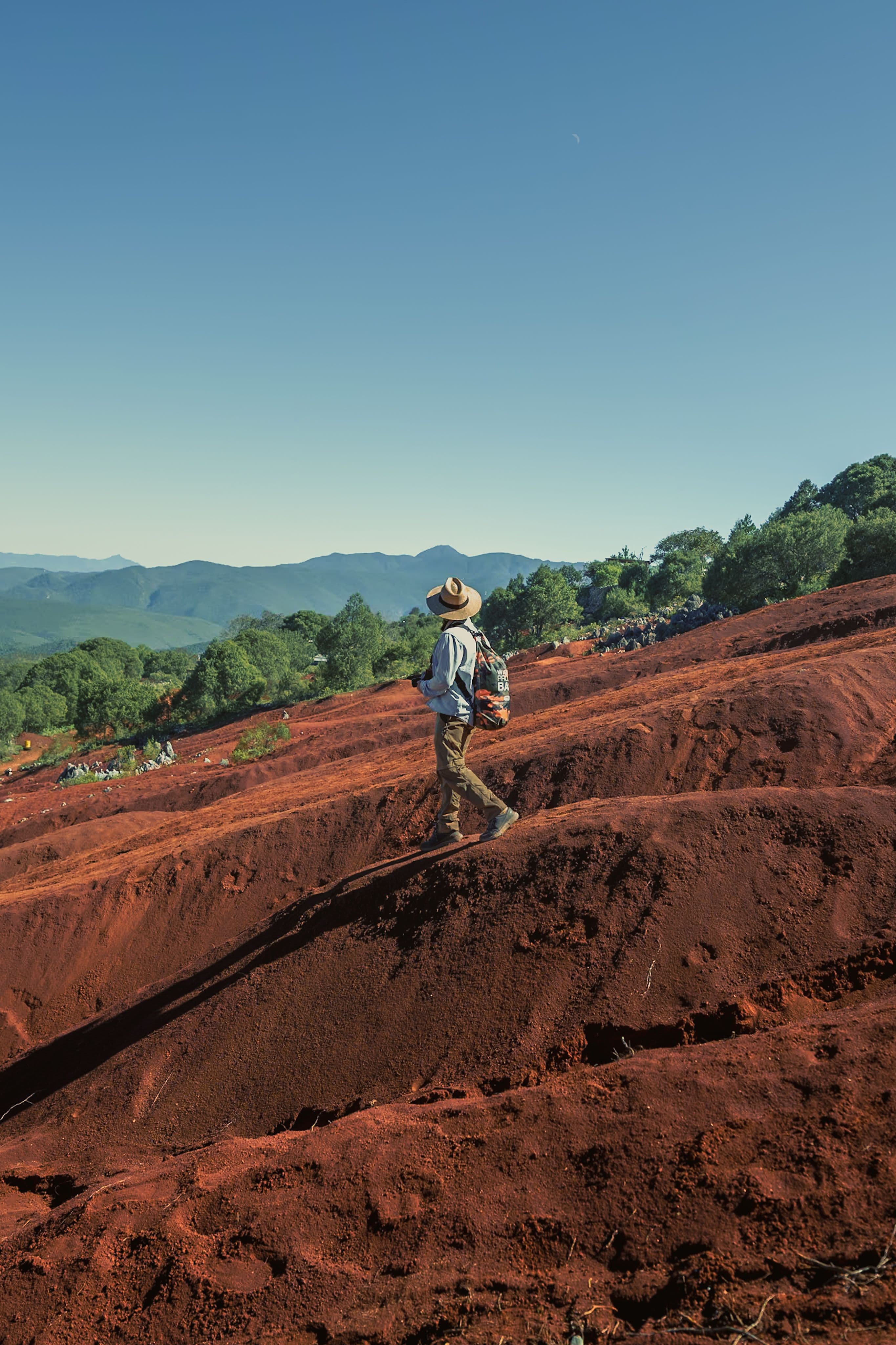 A hiker crossing the rippled red-earth dunes at Chamarel
