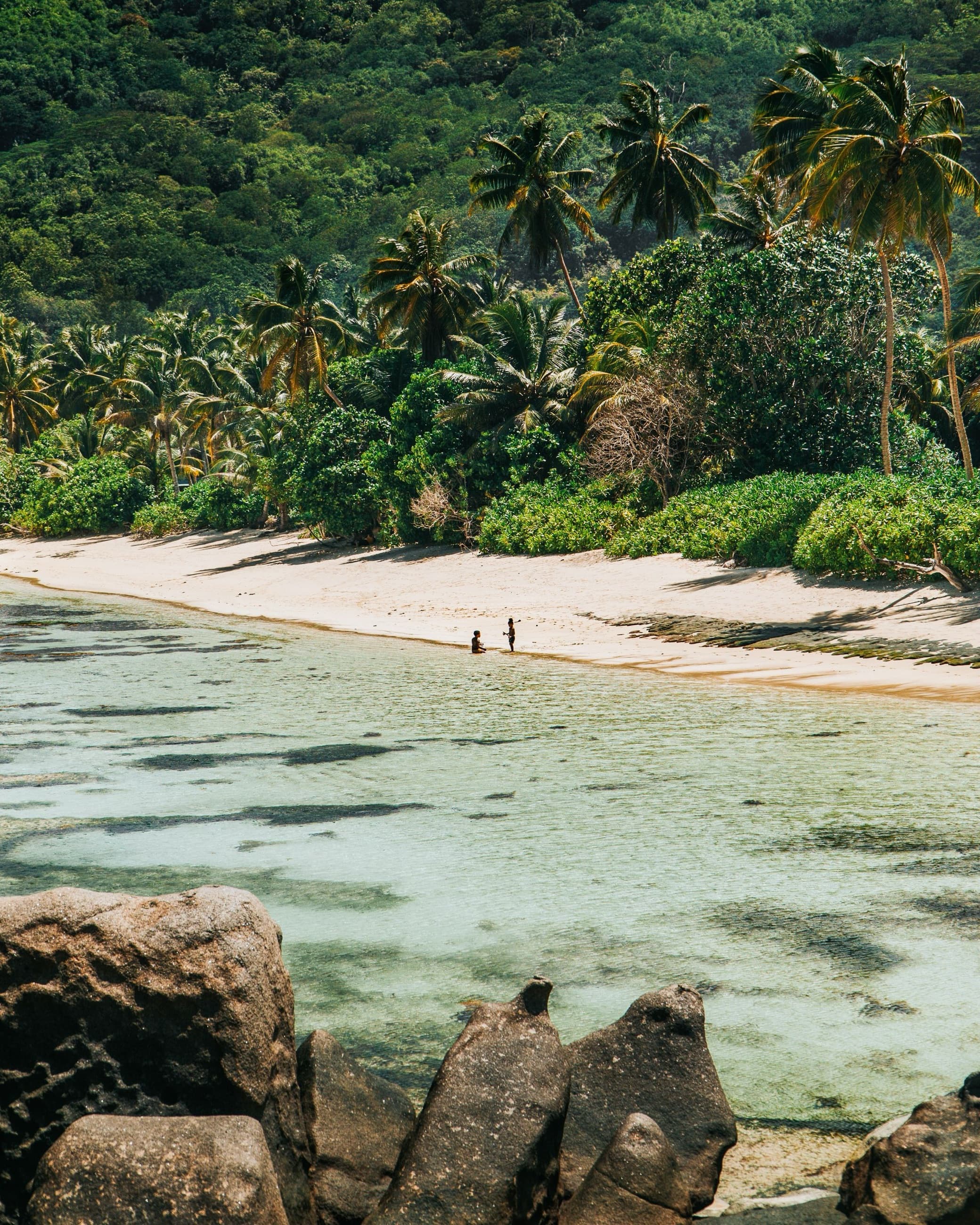 Weathered granite boulders framing a quiet turquoise beach on La Digue