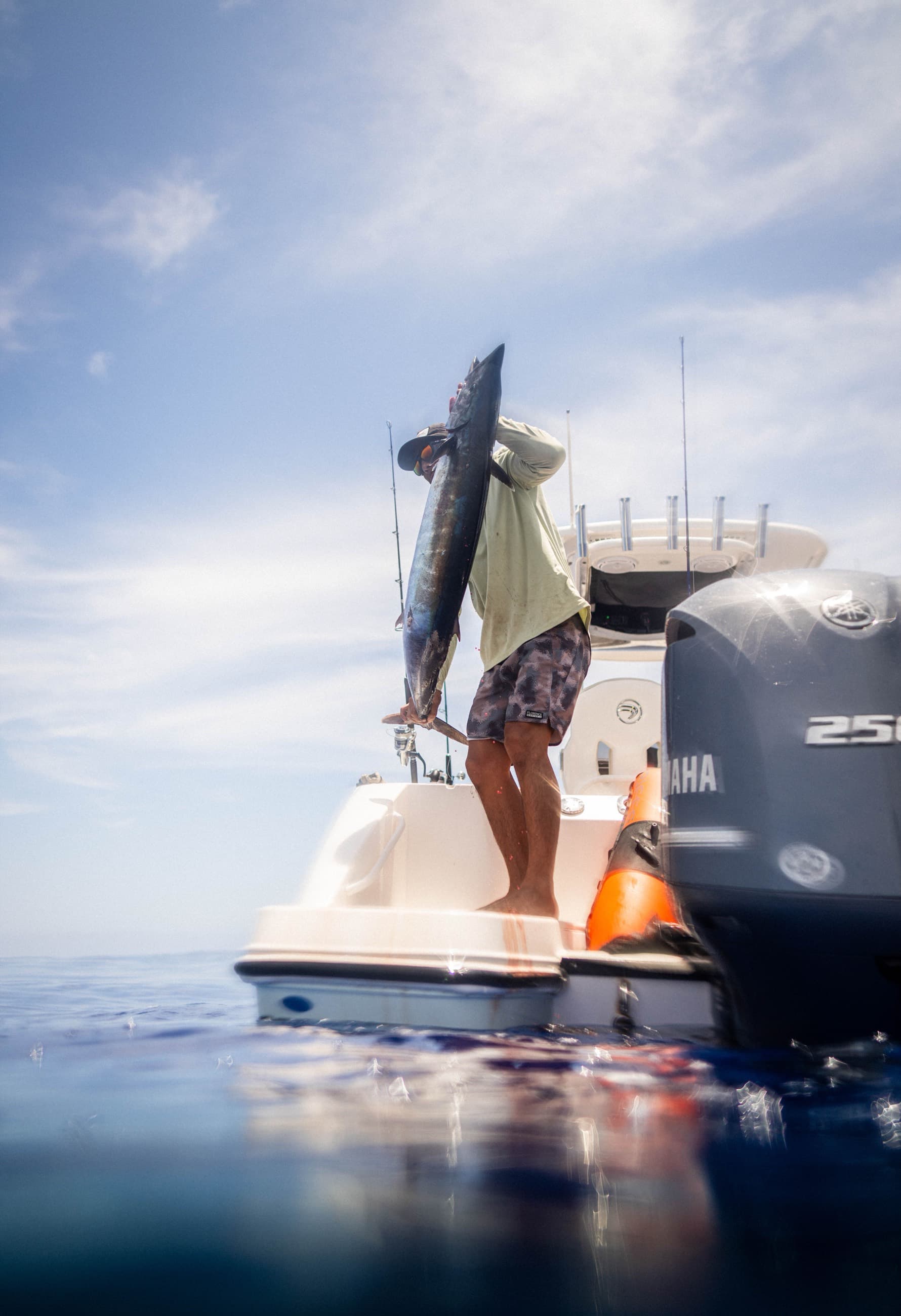 An angler hoisting a freshly caught gamefish aboard a deep-sea fishing boat