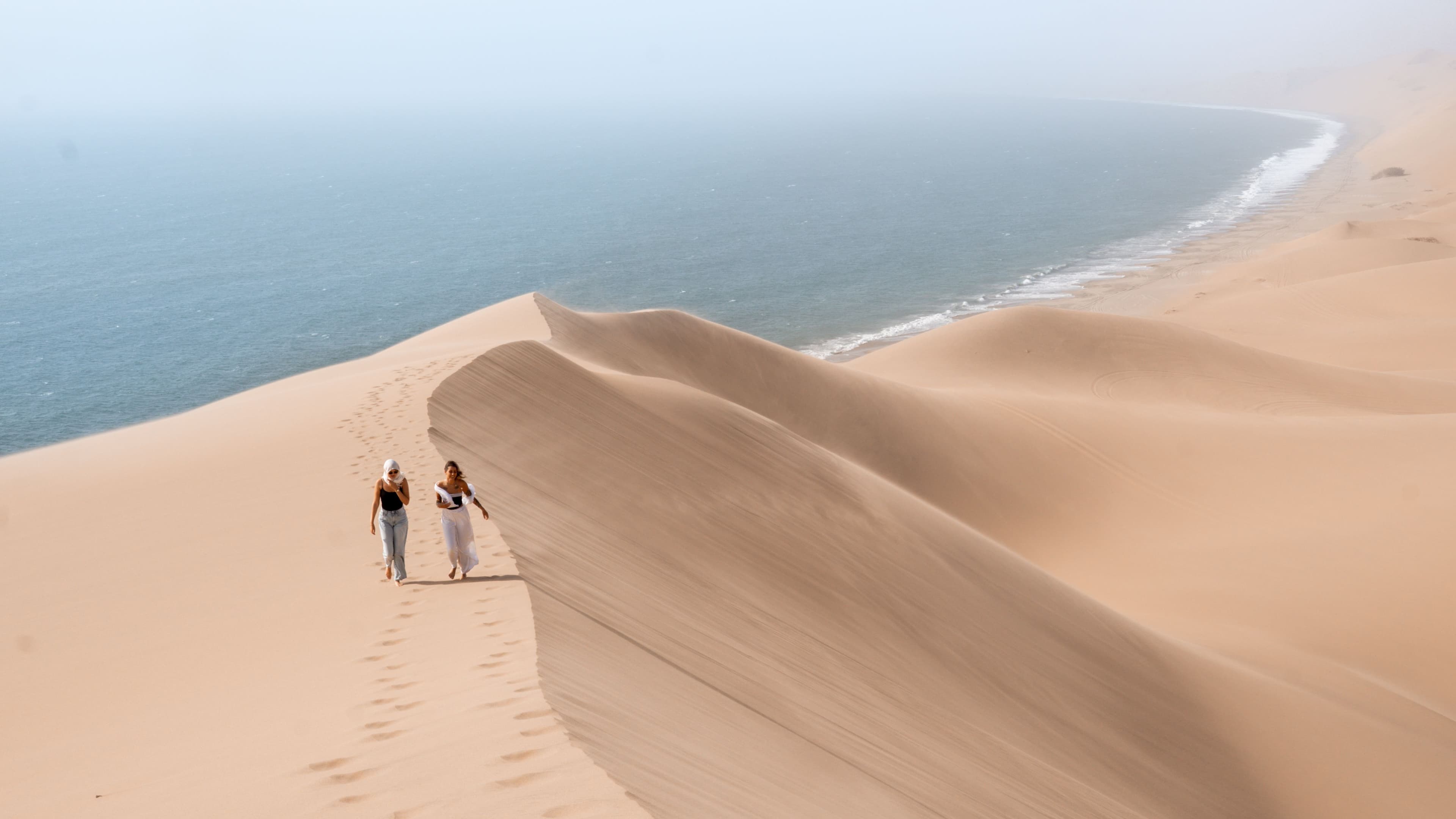 Two travelers walking the ridge of a dune above the Atlantic coast