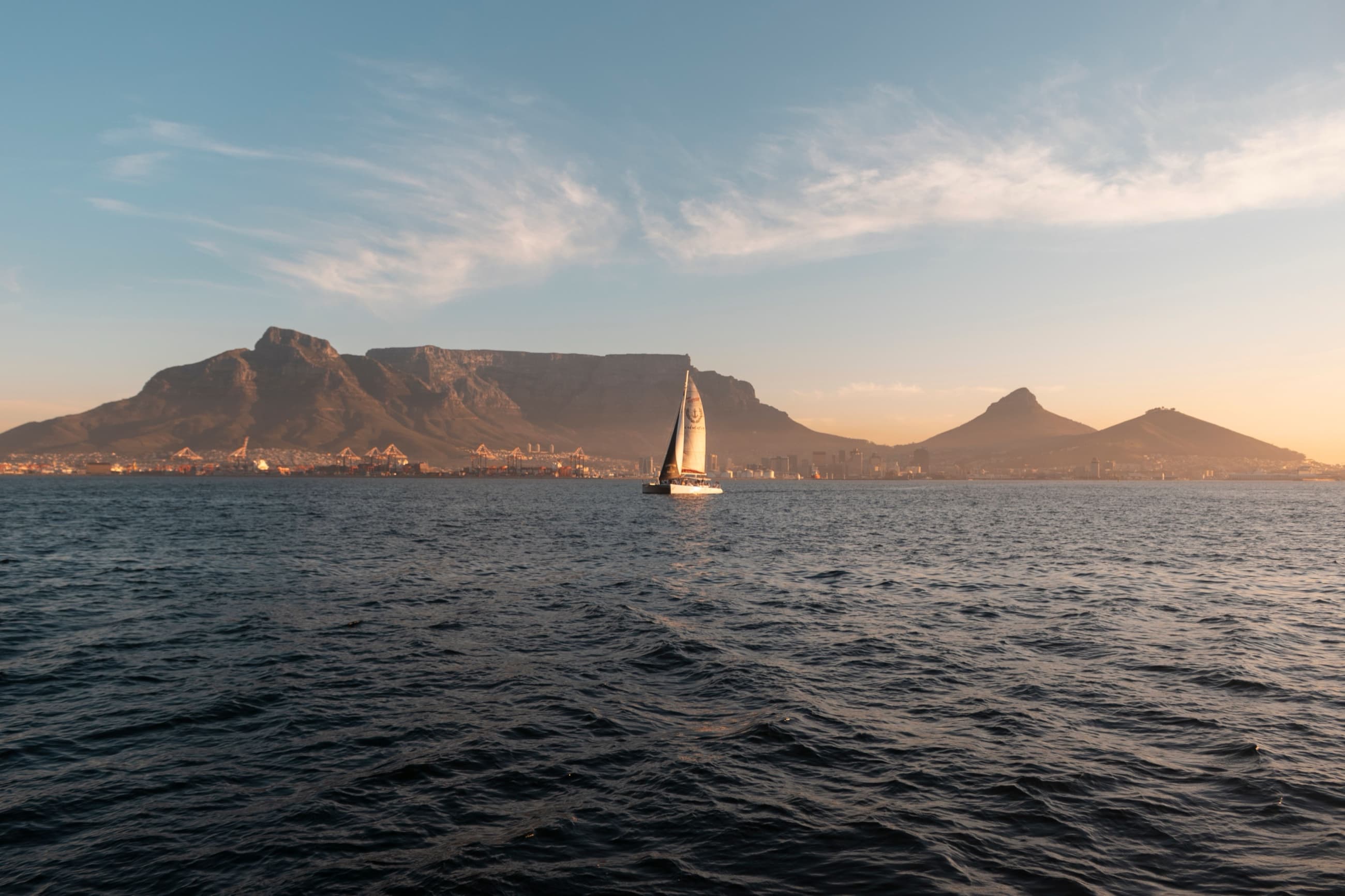 Sailboat crossing Table Bay at sunset with Table Mountain behind