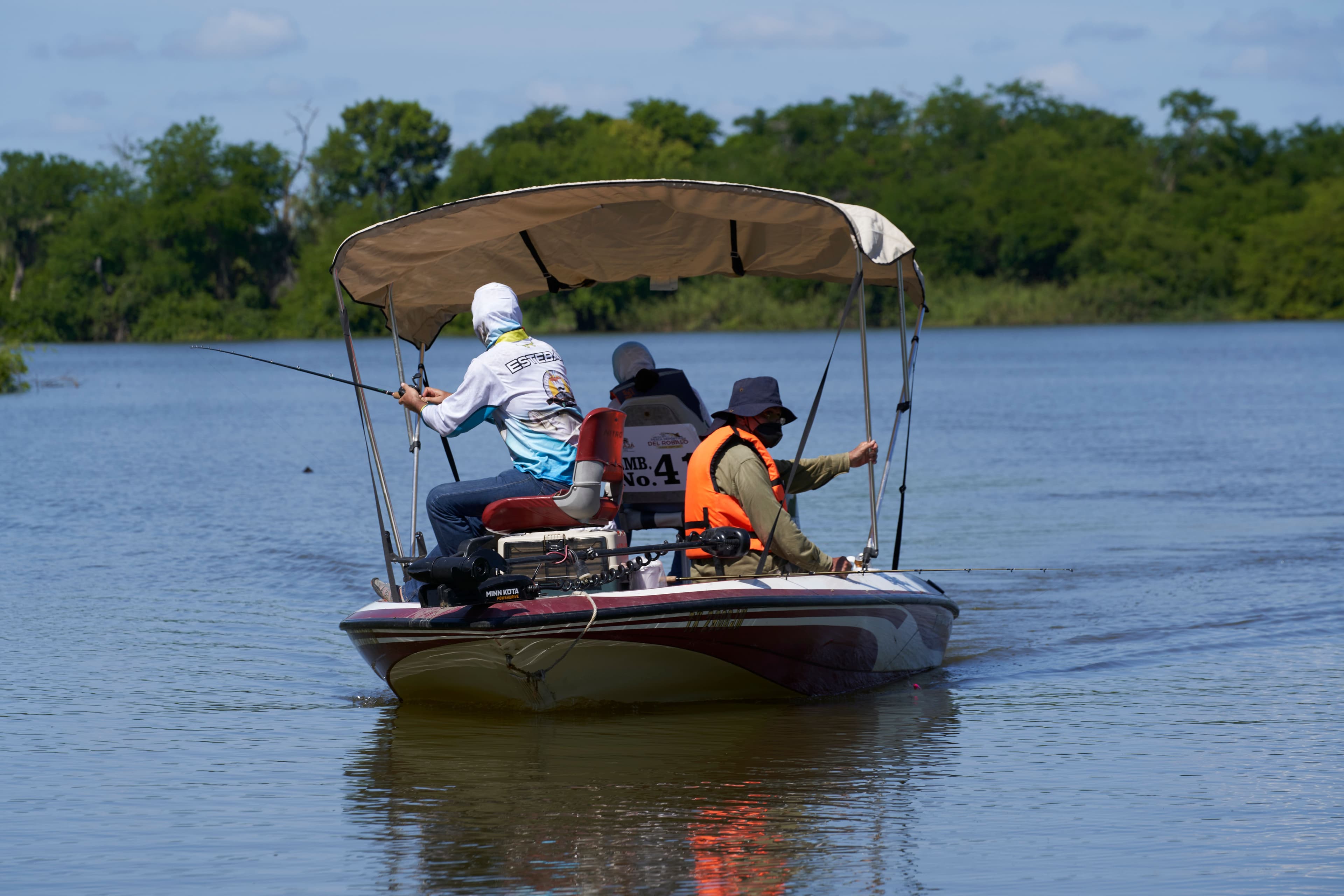 Anglers fishing from a canopied boat on the river